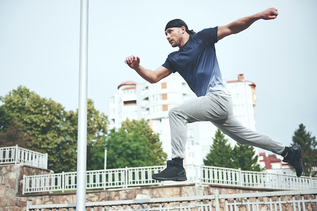 Junger Sportmann, der Parkour in der Stadt tut.