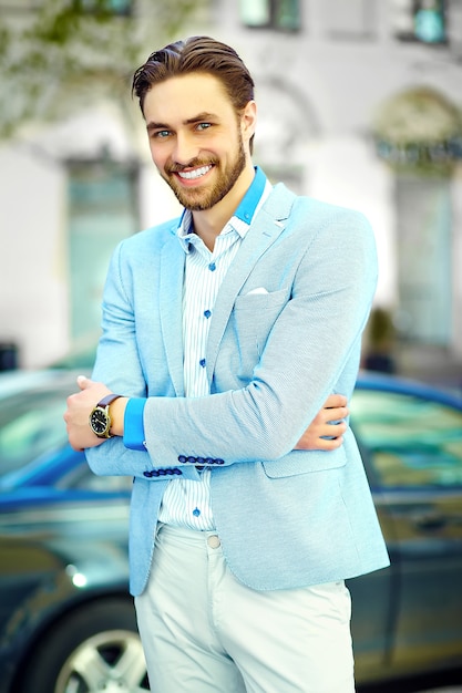 Junger stilvoller selbstbewusster glücklicher gutaussehender lächelnder Geschäftsmannmodellmann im blauen Anzugtuchlebensstil in der Straße
