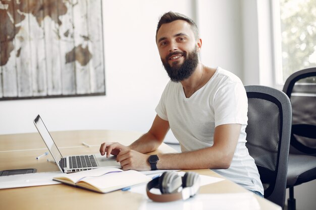 Junger Student, der am Tisch sitzt und den Laptop benutzt