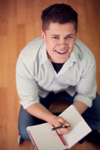 Kostenloses Foto junger student, der auf dem boden sitzt