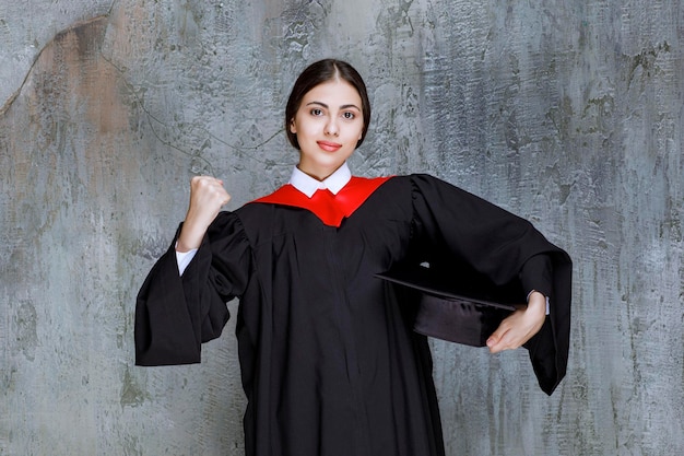 Junger Student im Kleid, das für Abschlusstag aufwirft. Foto in hoher Qualität