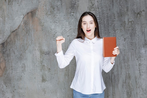 Junger Student oder Lehrer, der der Kamera ein Literaturbuch zeigt. Foto in hoher Qualität