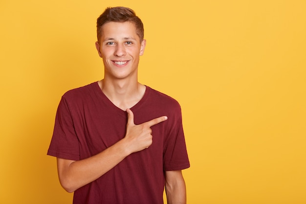 Junger Studentenmann, der mit seinem Zeigefinger beiseite zeigt