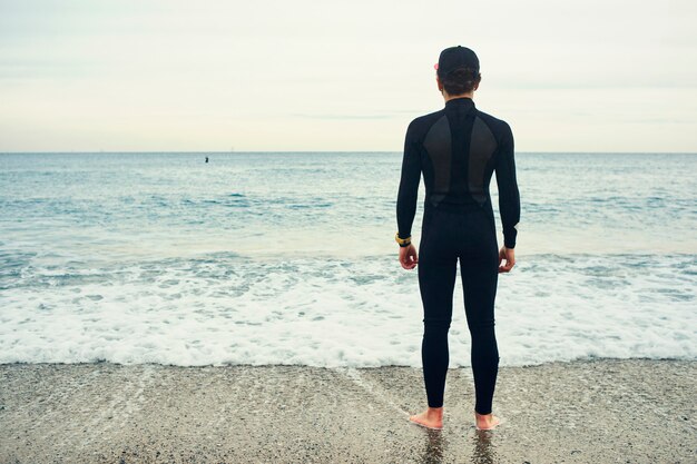 Junger Surfermann am Strand, der Mütze trägt