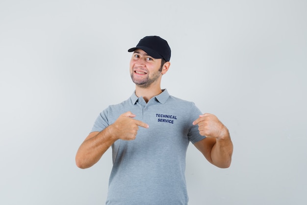 Kostenloses Foto junger techniker zeigt auf sein t-shirt in uniform und sieht stolz aus.