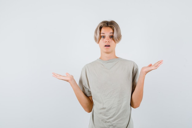 Junger Teenager, der hilflose Geste im T-Shirt zeigt und verwirrt schaut. Vorderansicht.