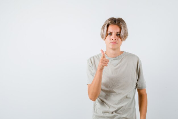 Junger Teenager, der im T-Shirt auf die Kamera zeigt und enttäuscht aussieht. Vorderansicht.