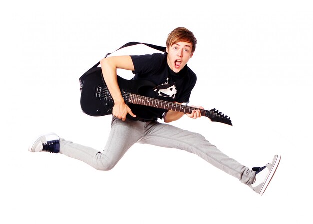 Junger Teenager, der mit Gitarre springt