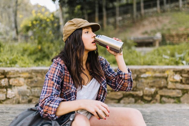 Junger Tourist, der von der Thermosflasche trinkt