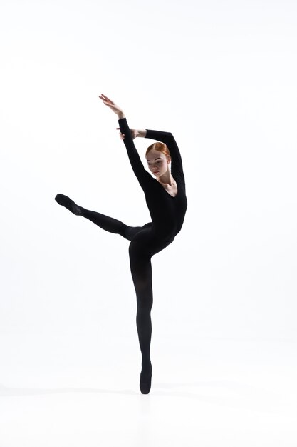 Junger und anmutiger Balletttänzer im minimalen schwarzen Stil lokalisiert auf weißem Studiohintergrund.