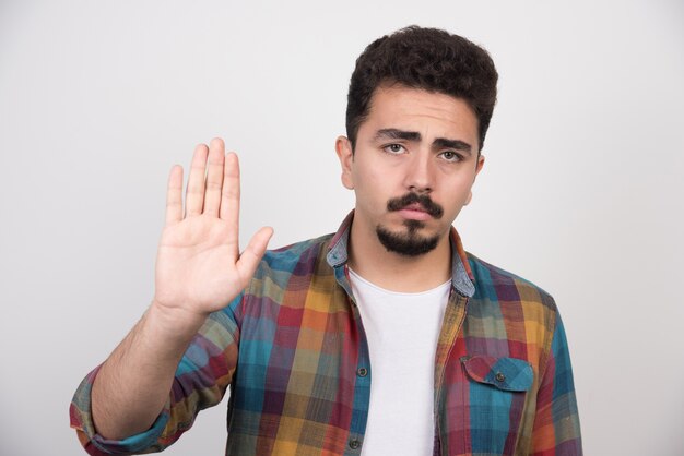 Junger unglücklicher Mann, der seine Hand hochhält und etwas verärgert, das er getan hat.