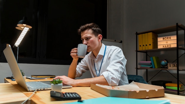 Kostenloses Foto junger unternehmer, der kaffee während der arbeit genießt