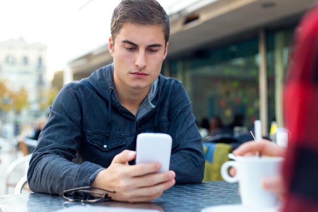 Junger Unternehmer, der seinen Handy an der Kaffeestube verwendet.