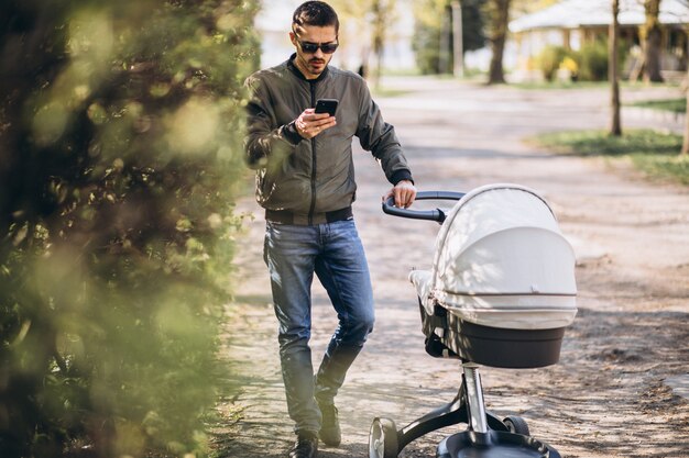 Kostenloses Foto junger vater, der mit kinderwagen im park geht