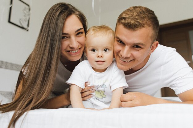 Junger Vater und Mutter freuen sich in den Armen ihres Kindes