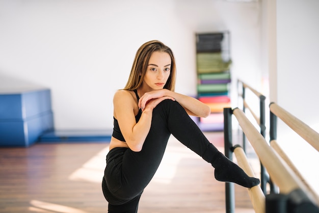 Junger weiblicher Tänzer, der ihre Beine ausdehnt