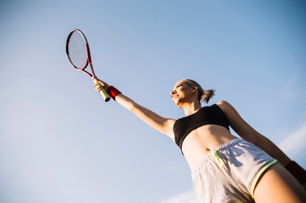 Junger weiblicher Tennisspieler des niedrigen Winkels, der Schläger hält