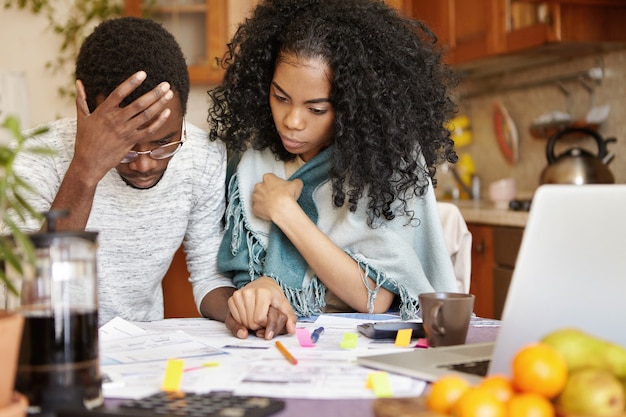 Junges afroamerikanisches Paar mit vielen Schulden, die Gas- und Stromrechnungen berechnen