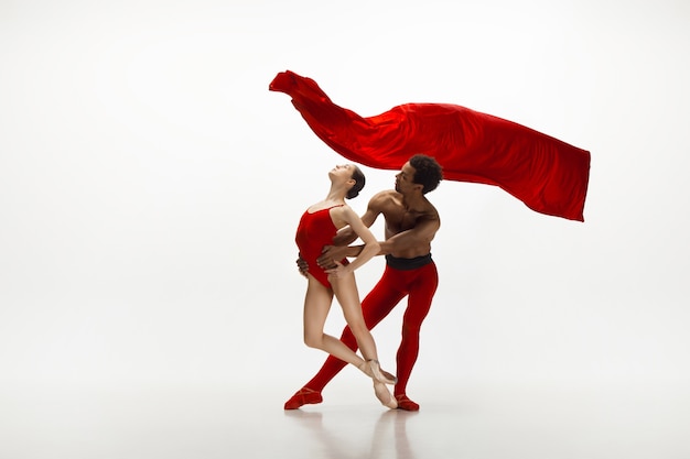 Junges anmutiges Paar Balletttänzer, die auf weißem Studiohintergrund tanzen