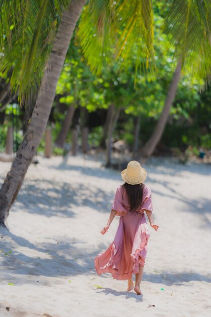 Junges asiatisches Frauenlächeln des Porträts glücklich um Strandseeozean mit KokosnussPalme für Feiertagsferien