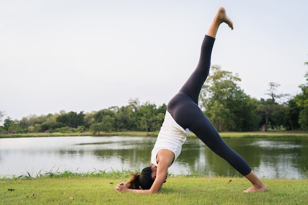 Junges asiatisches Frauenyoga draußen halten ruhig und meditieren beim Üben von Yoga