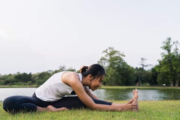 Junges asiatisches Frauenyoga draußen halten ruhig und meditieren beim Üben von Yoga