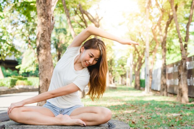 Junges asiatisches Frauenyoga draußen halten ruhig und meditieren beim Üben von Yoga