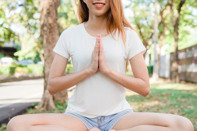 Junges asiatisches Frauenyoga draußen halten ruhig und meditieren beim Üben von Yoga