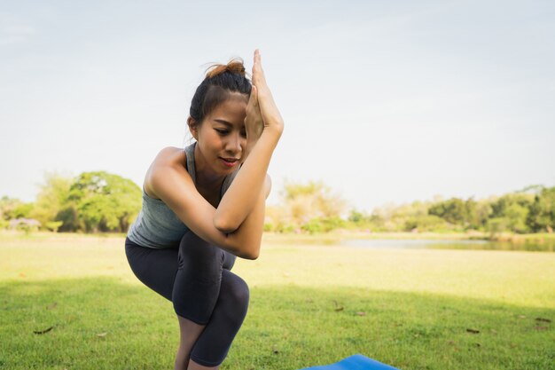 Junges asiatisches Frauenyoga draußen halten ruhig und meditieren beim Üben von Yoga