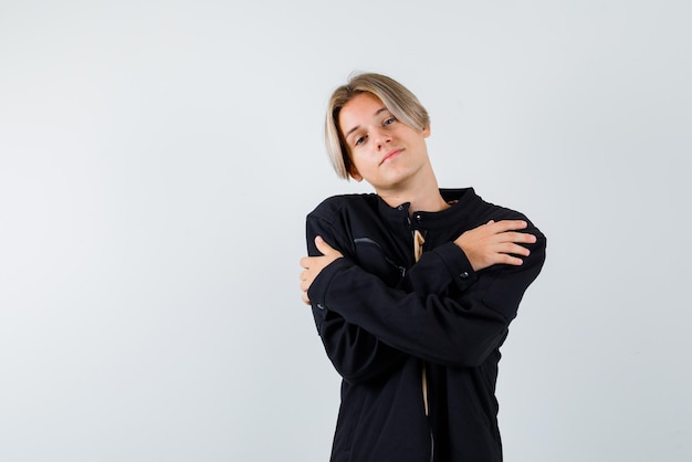 Junges blondes Mädchen, das ihre Arme auf weißem Hintergrund verschränkt