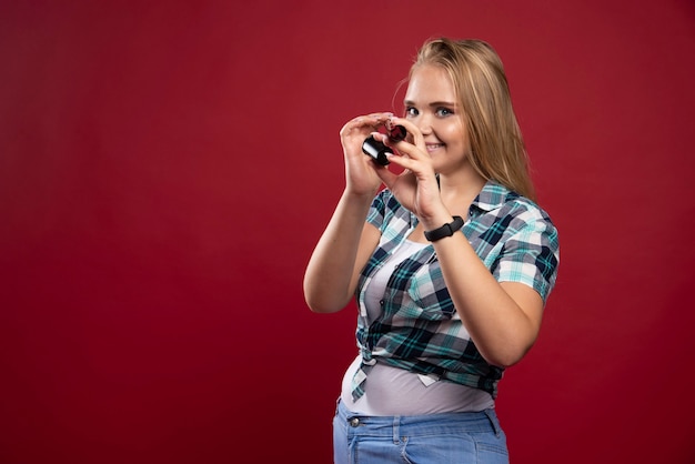 Junges blondes Model, das durch eine Polaroid-Filmröhre schaut und Spaß hat.