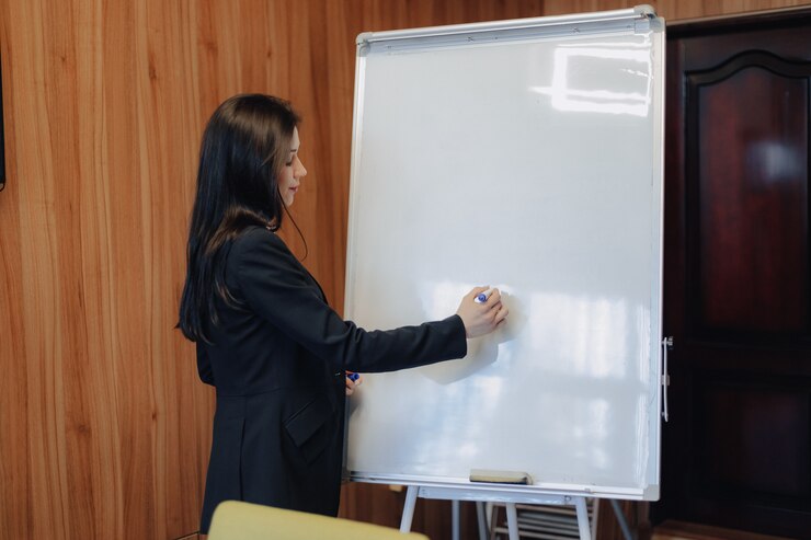 Kostenlose Foto junges emotionales attraktives mädchen in der geschäftsart kleidung, die mit flipchart in einem modernen büro oder in einem publikum arbeitet
