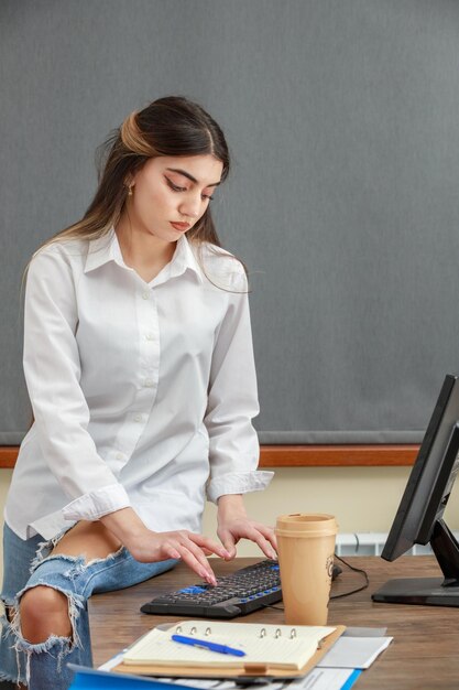 Junges entzückendes Mädchen, das im Büro arbeitet Foto in hoher Qualität