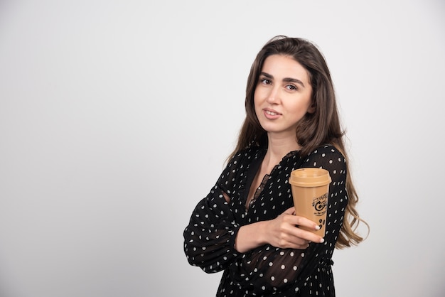 Junges Frauenmodell, das eine Kaffeetasse zeigt