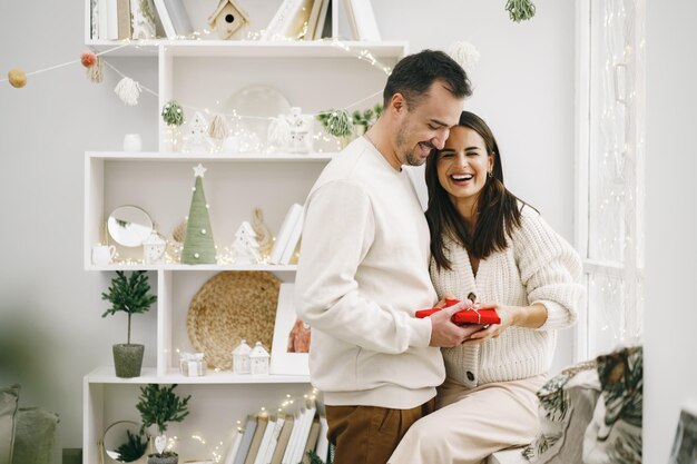 Junges fröhliches Paar verliebt in Geschenk zu Weihnachten