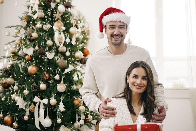 Junges fröhliches Paar verliebt in Geschenk zu Weihnachten