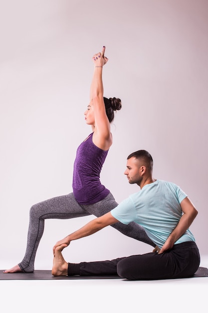 Junges gesundes Paar Mann und Frau in der Yoga-Position auf weißem Hintergrund