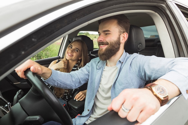 Junges glückliches Paar, das im Auto sitzt