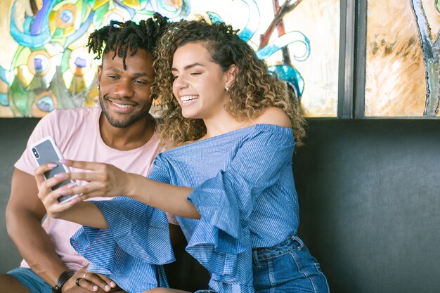 Junges glückliches Paar, das zusammen mit einem Handy ein Selfie macht, während es ein Date hat