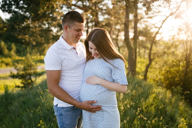 junges glückliches schönes Paar in der Liebe, die zusammen auf Gras- und Baumparklandschaft geht