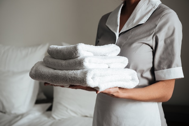 junges Hotelmädchen stehend und hält frische saubere Handtücher
