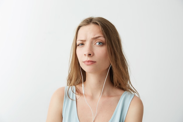 Junges hübsches Mädchen hebt die Stirn und hört Musik in Kopfhörern.