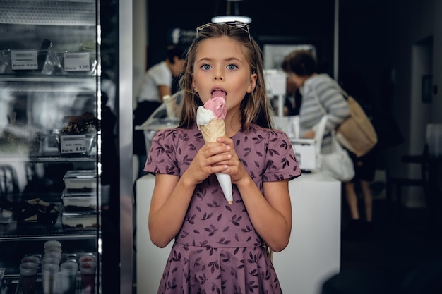 Junges hübsches Mädchen in einem Kleid, das Eis in einem Café isst.