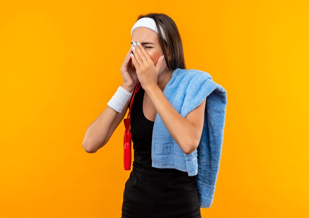 Junges hübsches sportliches Mädchen, das Stirnband und Armband mit Handtuch auf Schulter trägt