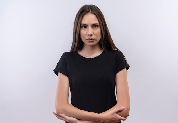 junges kaukasisches Mädchen, das schwarzes T-Shirt trägt, das Hände auf isolierter weißer Wand kreuzt