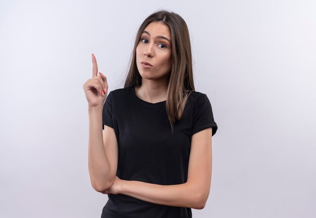 junges kaukasisches Mädchen, das schwarzes T-Shirt trägt, zeigt nach oben mit Finger auf isolierter weißer Wand