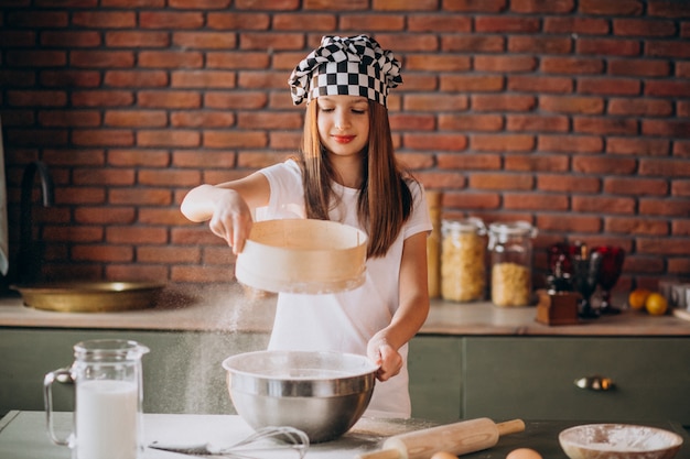 Junges kleines Mädchen, das Gebäck an der Küche zum Frühstück backt