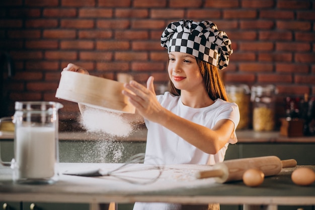 Kostenloses Foto junges kleines mädchen, das gebäck an der küche zum frühstück backt