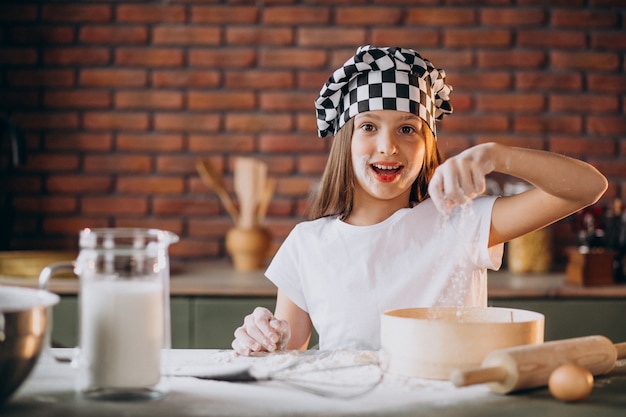 Junges kleines Mädchen, das Gebäck an der Küche zum Frühstück backt