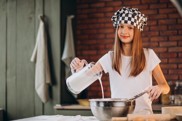 Junges kleines Mädchen, das Gebäck an der Küche zum Frühstück backt